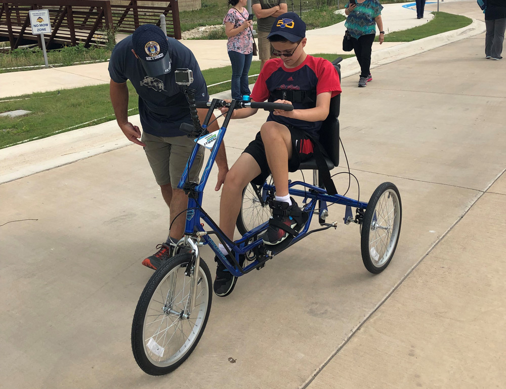 Jordan's dad, Tony, helps Jordan get onto his new Freedom Concepts Adaptive Bicycle